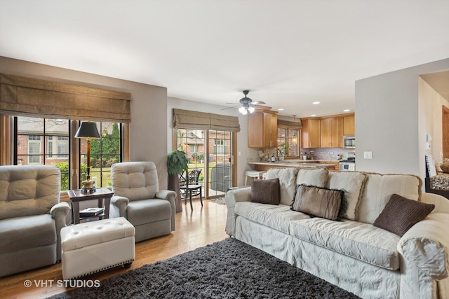 living room featuring ceiling fan and light hardwood / wood-style floors