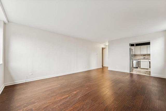 unfurnished living room featuring baseboards and wood finished floors