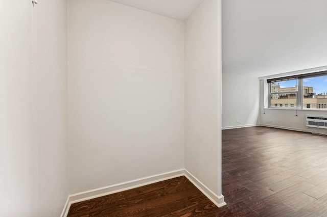 spare room with a wall mounted air conditioner, wood finished floors, and baseboards