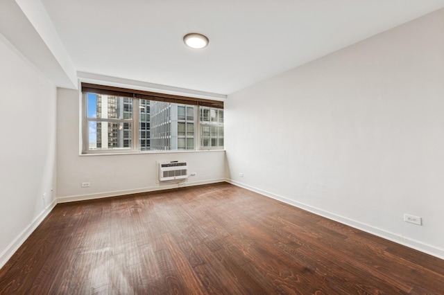 unfurnished room featuring an AC wall unit, wood finished floors, and baseboards