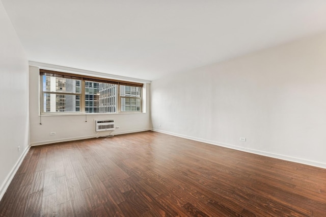 spare room featuring a wall unit AC, wood finished floors, and baseboards