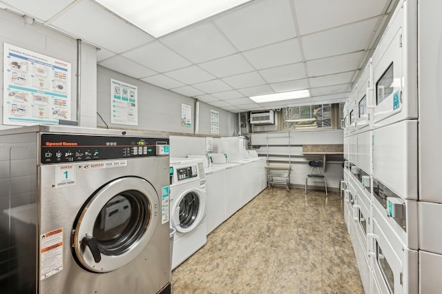 shared laundry area with washing machine and dryer, a wall unit AC, and stacked washing maching and dryer