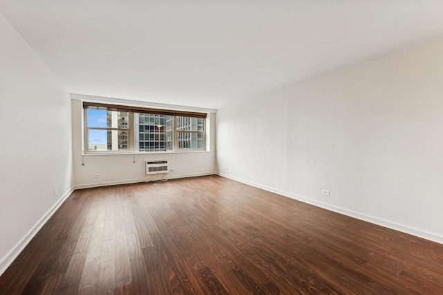 spare room with baseboards, dark wood finished floors, and a wall mounted air conditioner