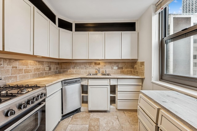 kitchen featuring light countertops, appliances with stainless steel finishes, a sink, and decorative backsplash