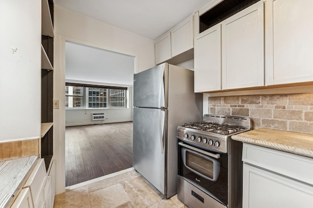 kitchen with tasteful backsplash, white cabinets, appliances with stainless steel finishes, a wall mounted air conditioner, and light countertops