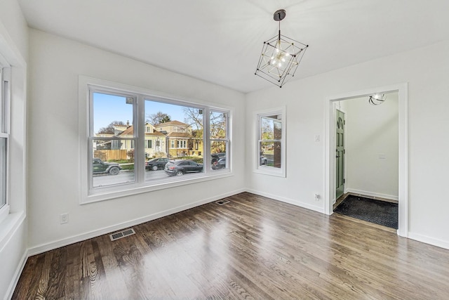 unfurnished dining area featuring a notable chandelier and dark hardwood / wood-style floors