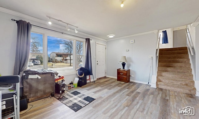 entryway featuring rail lighting, crown molding, and light hardwood / wood-style flooring