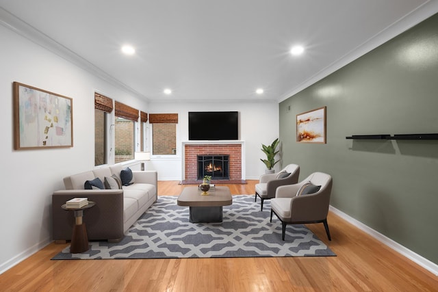 living room featuring hardwood / wood-style flooring, ornamental molding, and a brick fireplace