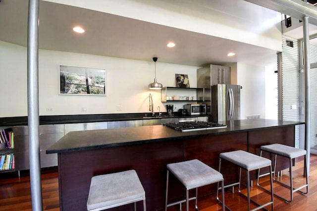 kitchen featuring a kitchen breakfast bar, sink, dark wood-type flooring, and appliances with stainless steel finishes