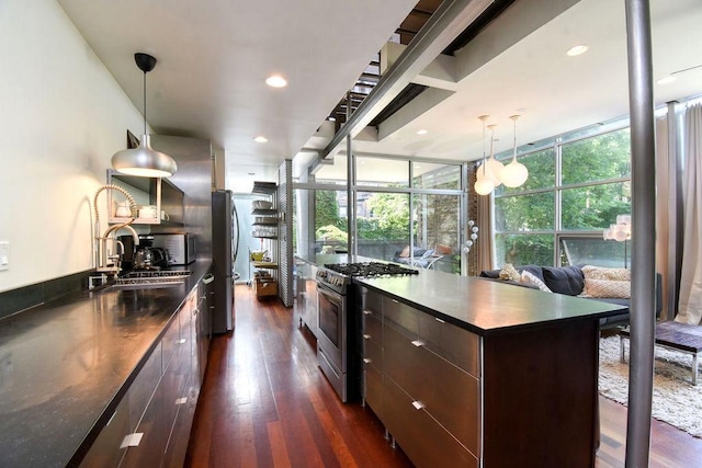 kitchen with appliances with stainless steel finishes, dark brown cabinetry, sink, decorative light fixtures, and dark hardwood / wood-style floors