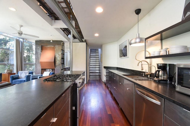 kitchen featuring ceiling fan, sink, dark wood-type flooring, hanging light fixtures, and appliances with stainless steel finishes