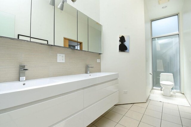 bathroom with tile patterned flooring, vanity, toilet, and backsplash