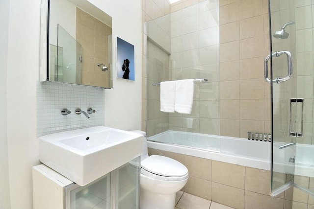 bathroom featuring tile patterned flooring, tasteful backsplash, toilet, and bath / shower combo with glass door