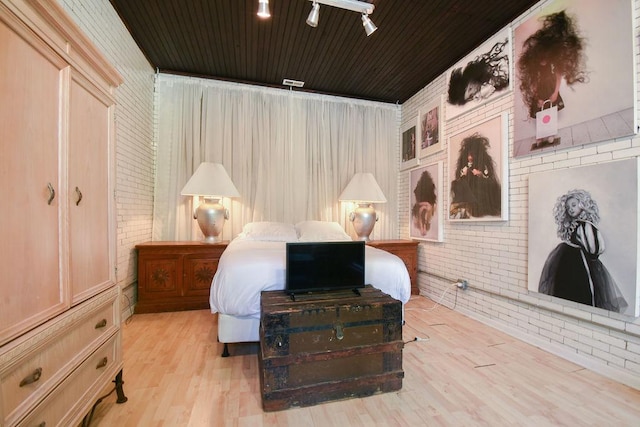 bedroom with light hardwood / wood-style flooring, wooden ceiling, and brick wall