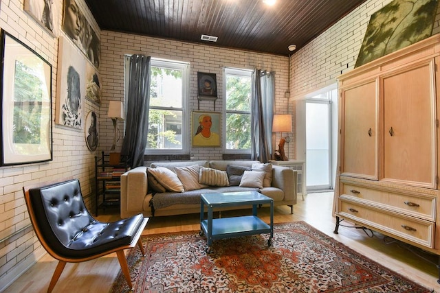 sitting room with light wood-type flooring, wooden ceiling, and brick wall