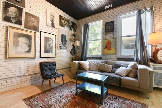 sitting room featuring hardwood / wood-style floors, radiator heating unit, wood ceiling, and brick wall