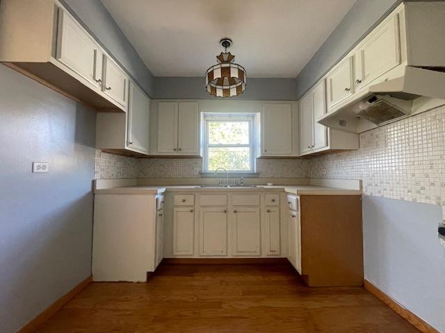 kitchen featuring decorative backsplash, sink, white cabinets, and hardwood / wood-style floors