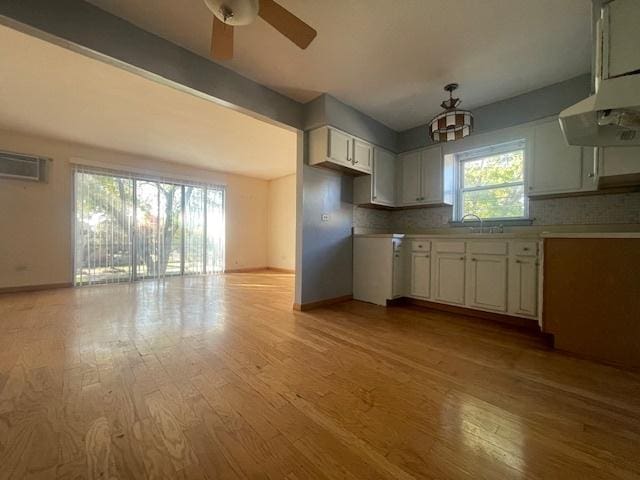 kitchen with tasteful backsplash, white cabinets, ceiling fan, light hardwood / wood-style floors, and sink