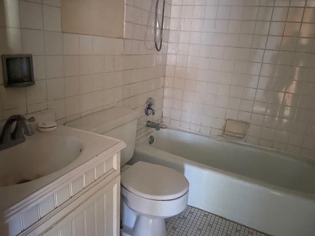 full bathroom featuring tile patterned flooring, toilet, tile walls, vanity, and tiled shower / bath combo