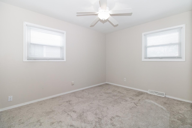 empty room with light colored carpet, a wealth of natural light, and ceiling fan