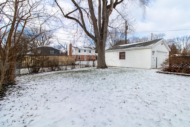 yard covered in snow featuring an outbuilding and a garage