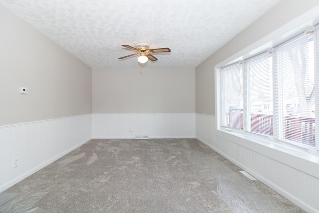 unfurnished room with ceiling fan, carpet floors, and a textured ceiling