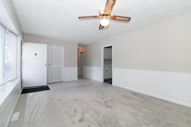 carpeted empty room featuring ceiling fan and a textured ceiling