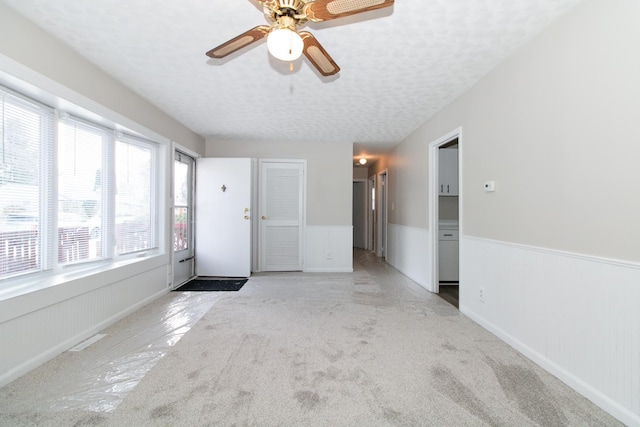 carpeted empty room with ceiling fan and a textured ceiling