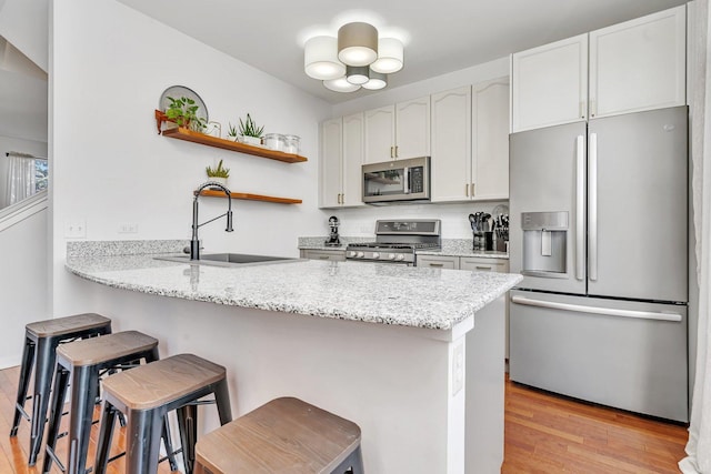 kitchen featuring appliances with stainless steel finishes, kitchen peninsula, a breakfast bar area, and white cabinets