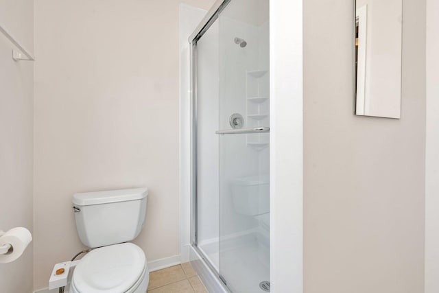 bathroom featuring toilet, a shower with shower door, and tile patterned flooring