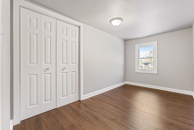 unfurnished bedroom with dark wood-type flooring and a closet