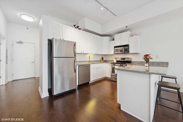 kitchen with white cabinets, a kitchen breakfast bar, tasteful backsplash, kitchen peninsula, and stainless steel appliances