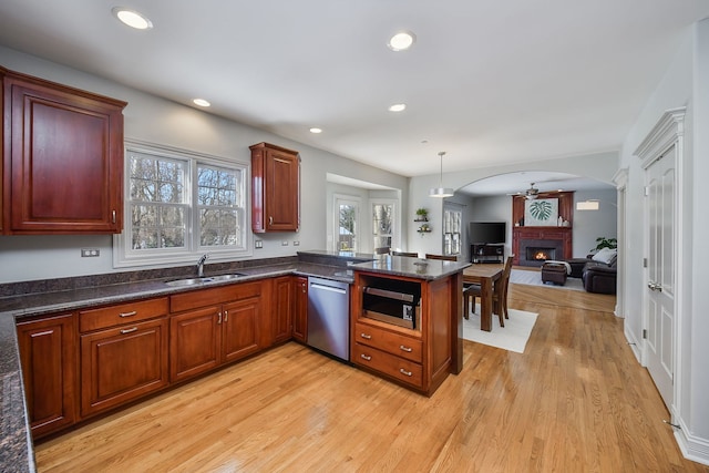 kitchen featuring appliances with stainless steel finishes, hanging light fixtures, light wood-type flooring, kitchen peninsula, and sink