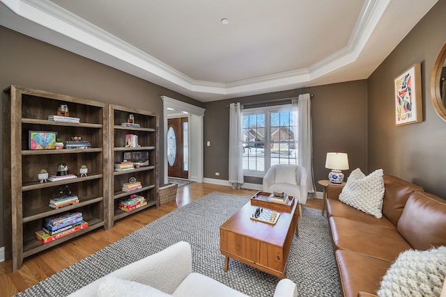 living room featuring light wood-type flooring, a tray ceiling, and crown molding