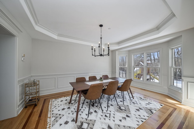 dining room featuring a notable chandelier, ornamental molding, a raised ceiling, and wood-type flooring