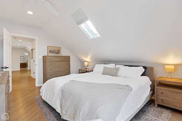 bedroom featuring lofted ceiling with skylight, ceiling fan, and light hardwood / wood-style flooring