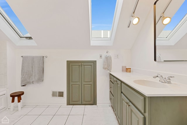 bathroom featuring lofted ceiling with skylight, tile patterned floors, and vanity