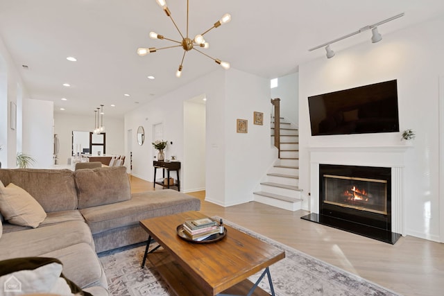 living room featuring a chandelier, track lighting, and light wood-type flooring