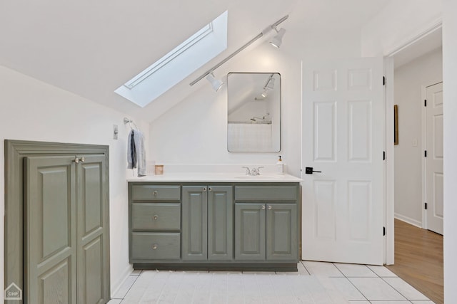 bathroom featuring vanity, tile patterned floors, lofted ceiling with skylight, and rail lighting