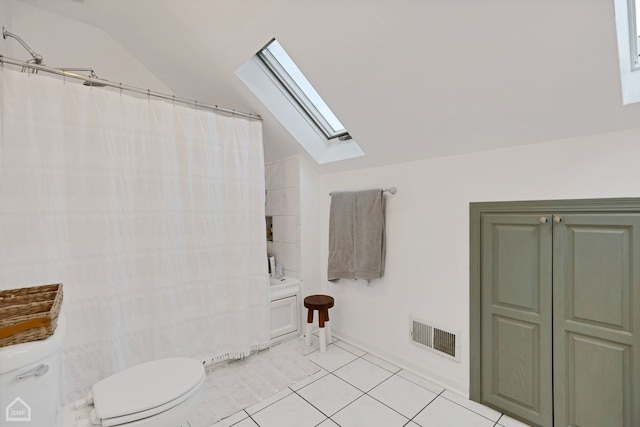 bathroom featuring toilet, tile patterned floors, and lofted ceiling with skylight