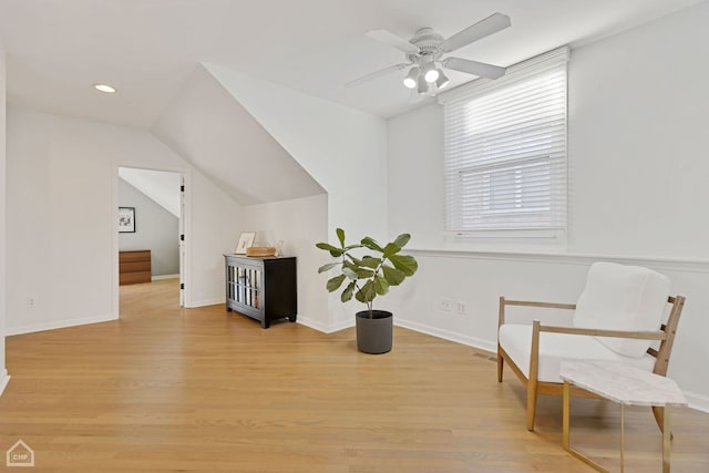 living area featuring light hardwood / wood-style flooring, ceiling fan, and vaulted ceiling