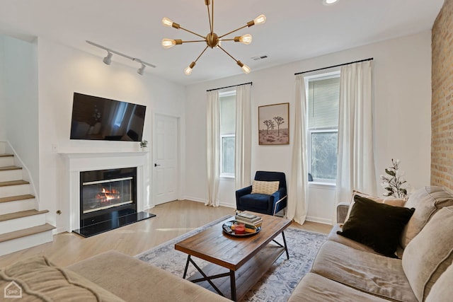 living room with rail lighting, light hardwood / wood-style floors, and a notable chandelier