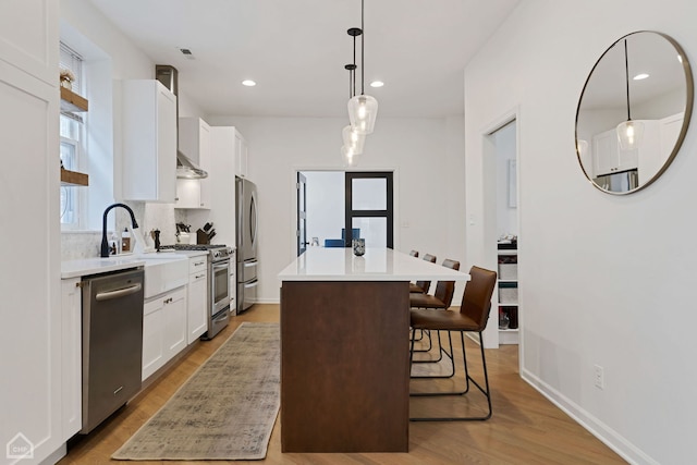 kitchen featuring white cabinetry, stainless steel appliances, a center island, a kitchen breakfast bar, and decorative light fixtures