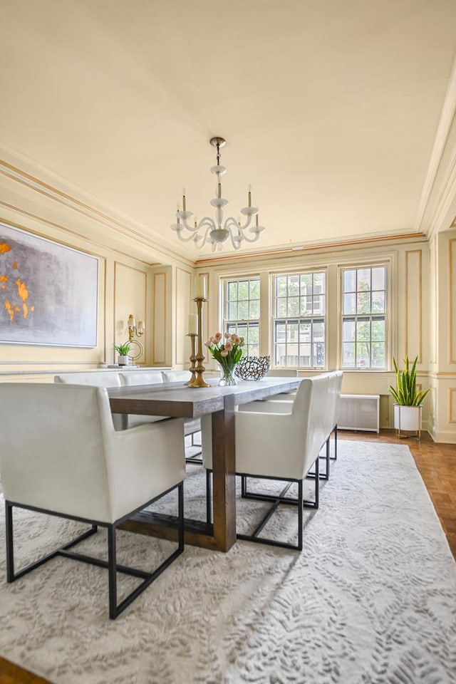 dining area featuring wood-type flooring, radiator heating unit, ornamental molding, and a notable chandelier