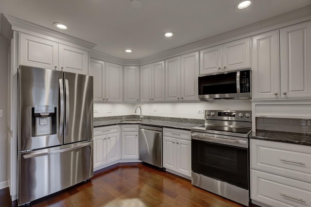 kitchen with dark hardwood / wood-style floors, tasteful backsplash, sink, white cabinets, and stainless steel appliances