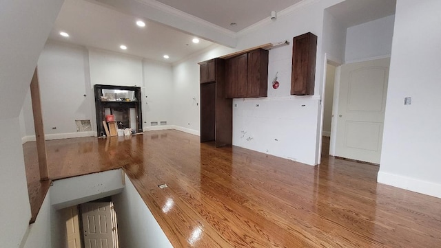 unfurnished living room with wood-type flooring and crown molding