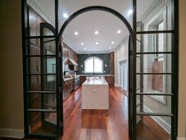 kitchen with dark hardwood / wood-style floors, a kitchen island, and ornamental molding