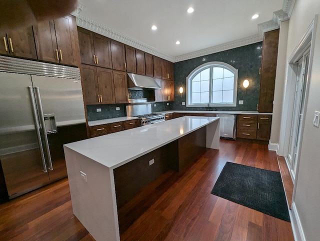 kitchen with a center island, dark hardwood / wood-style floors, appliances with stainless steel finishes, tasteful backsplash, and dark brown cabinetry