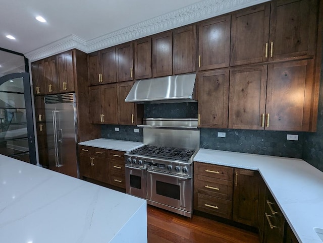 kitchen with backsplash, dark brown cabinets, dark wood-type flooring, and high end appliances