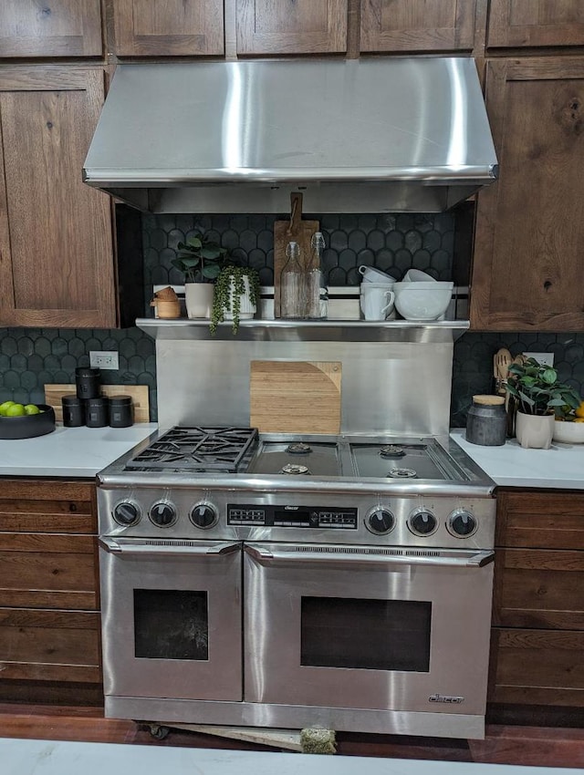 kitchen with tasteful backsplash, exhaust hood, and range with two ovens